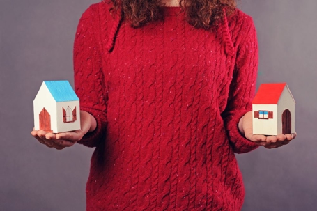 woman in red holding two small houses