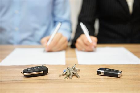two people signing a divorce agreement with their keys sitting in front of them on the table